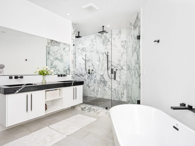 A modern white bathroom with a luxurious marble countertop and a bathtub